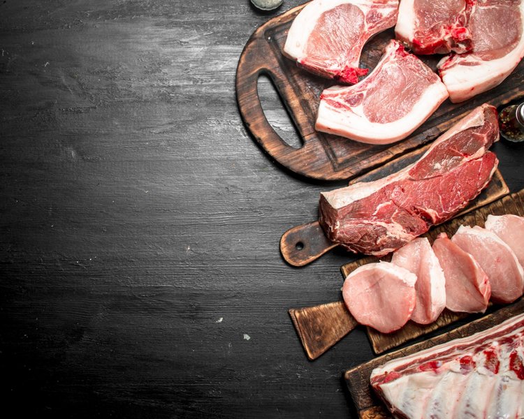 pork_mixedcuts1 Succulent pulled pork on a wooden cutting board, showcasing tender, shredded meat with a crispy outer layer. A fork rests beside the meat, highlighting its juicy texture and rich seasoning.
